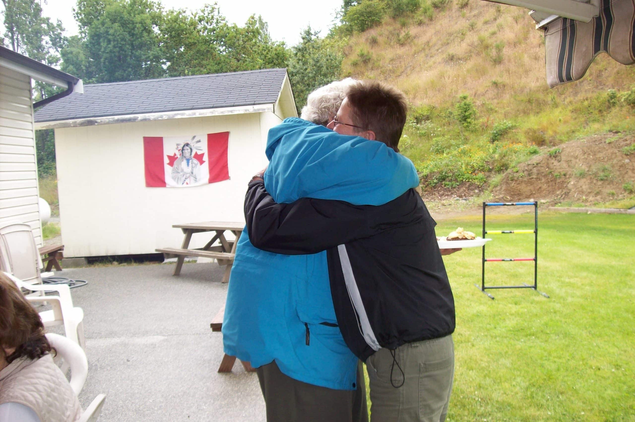 Residents outside the old Buttertubs seniors community hall hug.