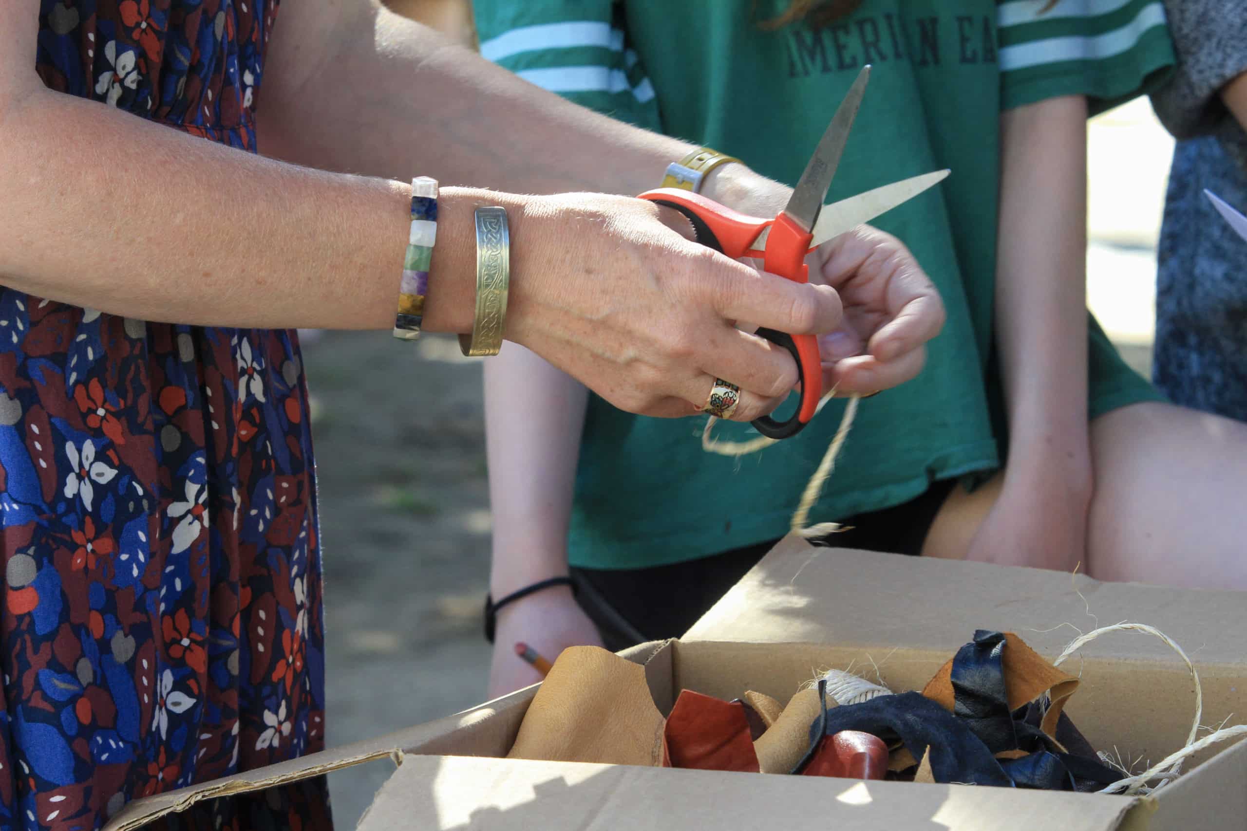 Close up of hands holding a pair of scissors and cut string.
