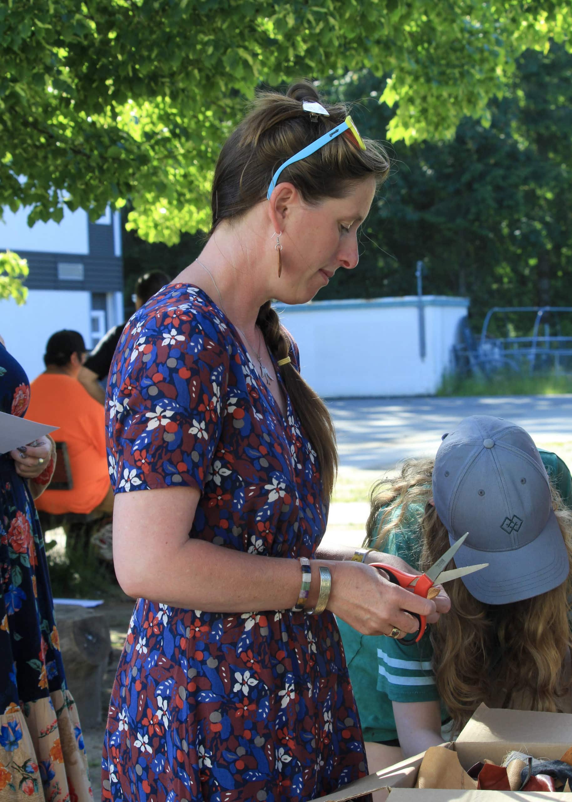 Side profile of a woman holding looking down, holding a pair of scissors and string in her hands.