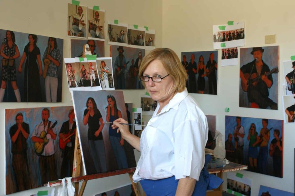 Painter Gerda Hofman is shown in her Commercial Street studio in 2009, surrounded by red-hued paintings of performers, before it burned down in 2016.