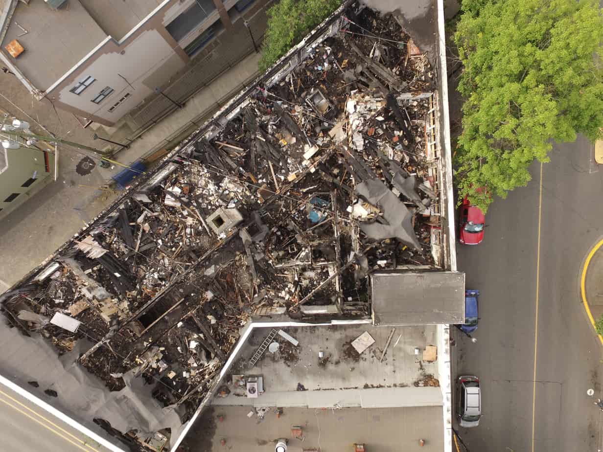 An overhead view of the fire-damaged roof of the Jean Burns building. To the right is Commercial Street, along the upper-left is what is known as the China Steps.