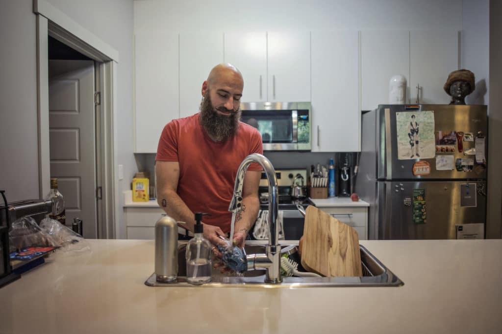 Jon Galliazzo washes dishes in his Linley Valley Drive apartment. Like many tenants, he's confused by vague and inflated charges for water by a sub-metering company