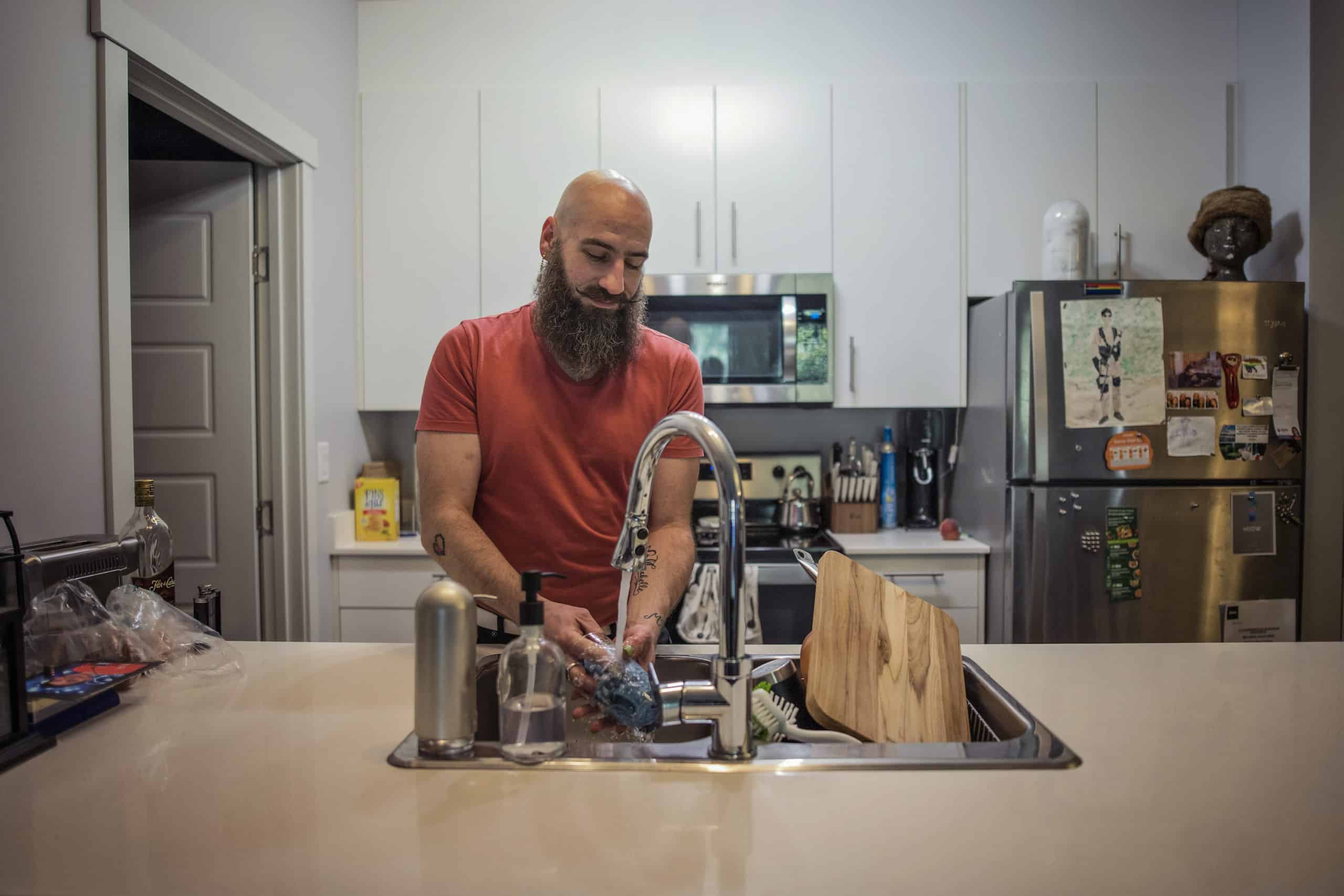 Jon Galliazzo washes dishes in his Linley Valley Drive apartment. Like many tenants, he's confused by vague and inflated charges for water by a sub-metering company