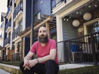 A Nanaimo resident since in front of their apartment complex wearing a red shirt.