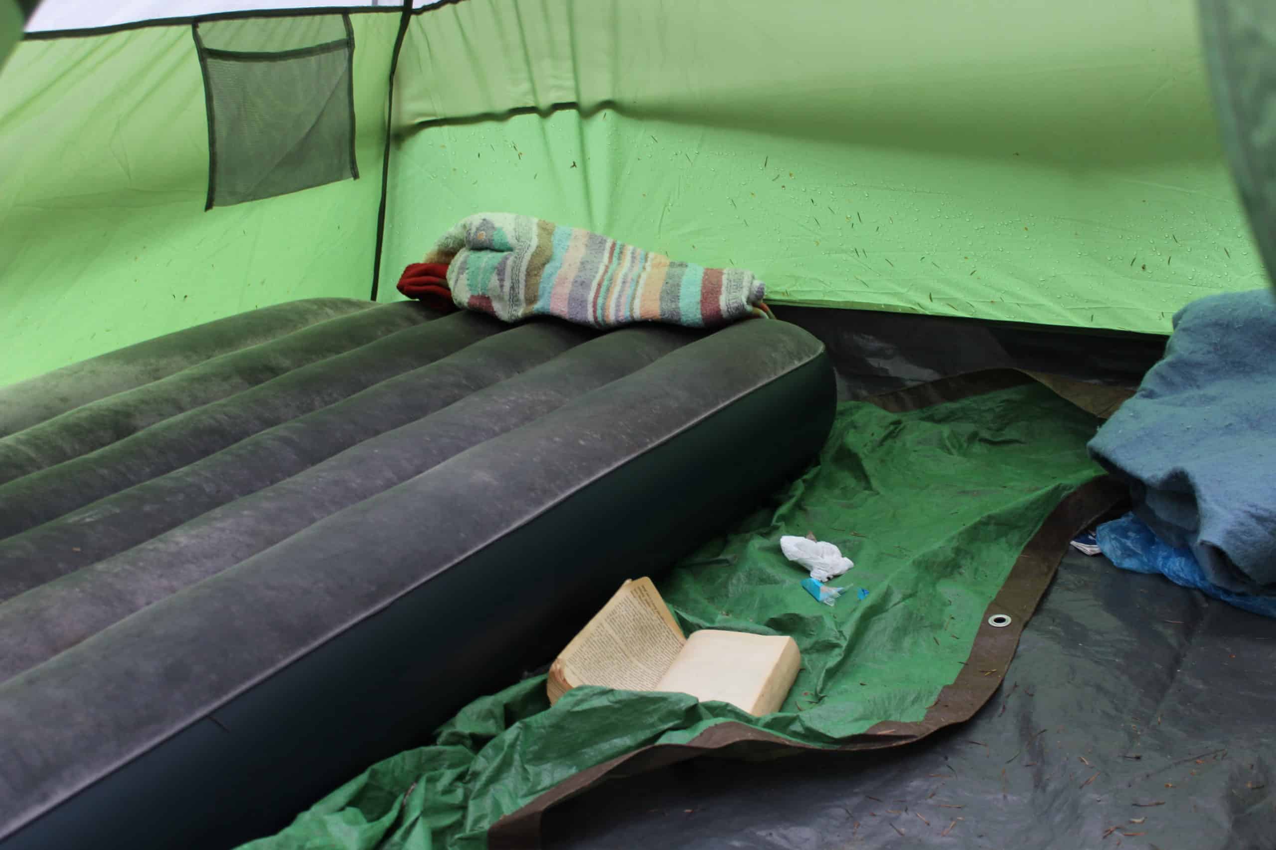 Inside Randy's green tent, where a bare blow-up mattress, a tarp, a paperback book and some blankets remain.