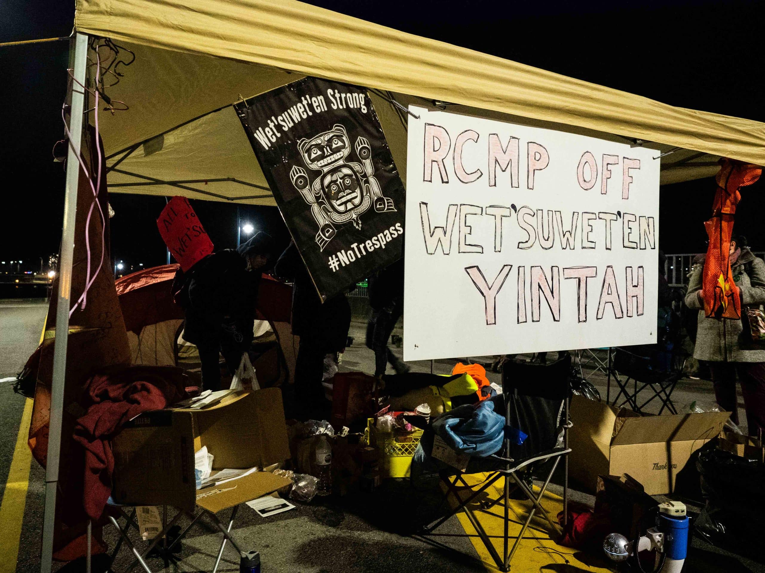 Signs hang off a canopy tent that read "RCMP off Wet’suwet’en yintah" and "Wet’suwet’en strong #notresspass."