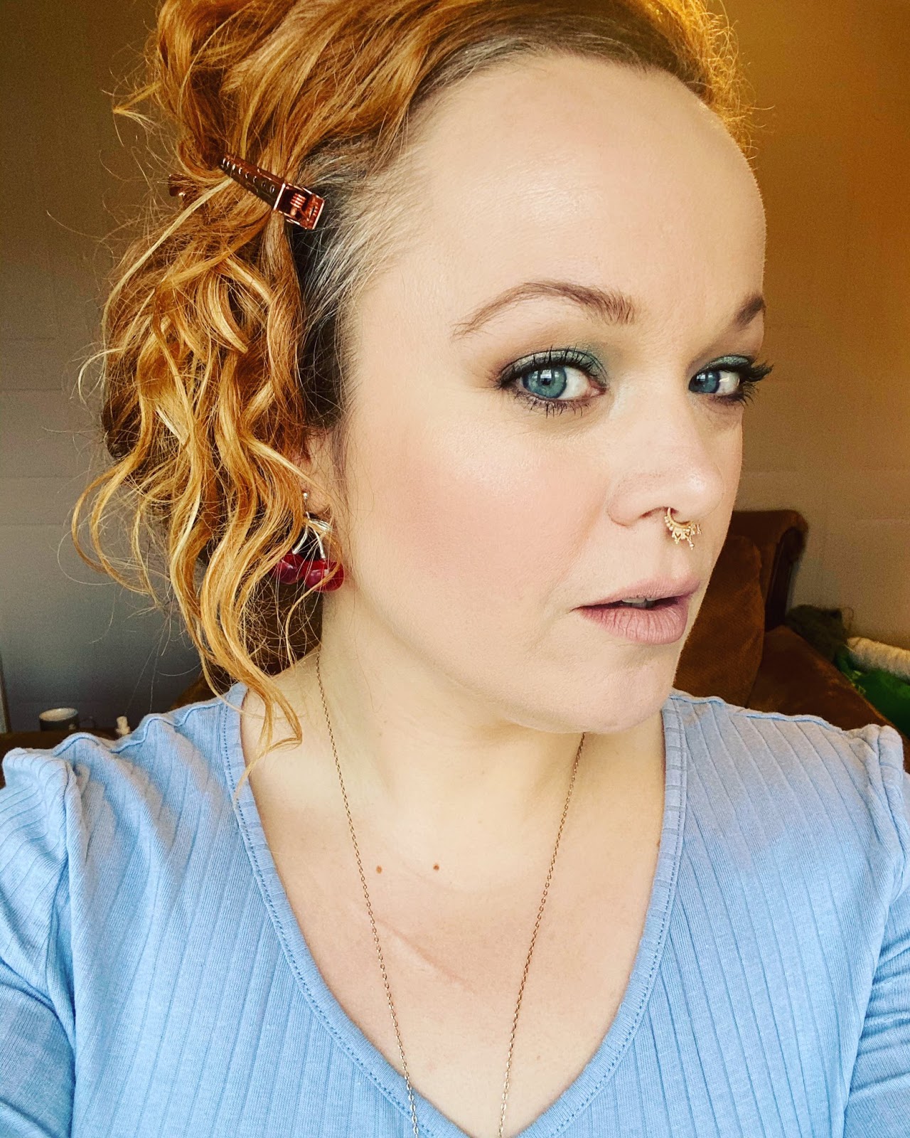 A closeup of a woman with green eyes, eyeliner and strawberry blonde curls.