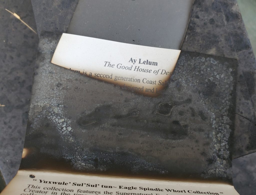 A charred piece of paper with an unburned patch that reads “Ay Lelum. The Good House of Design.”
