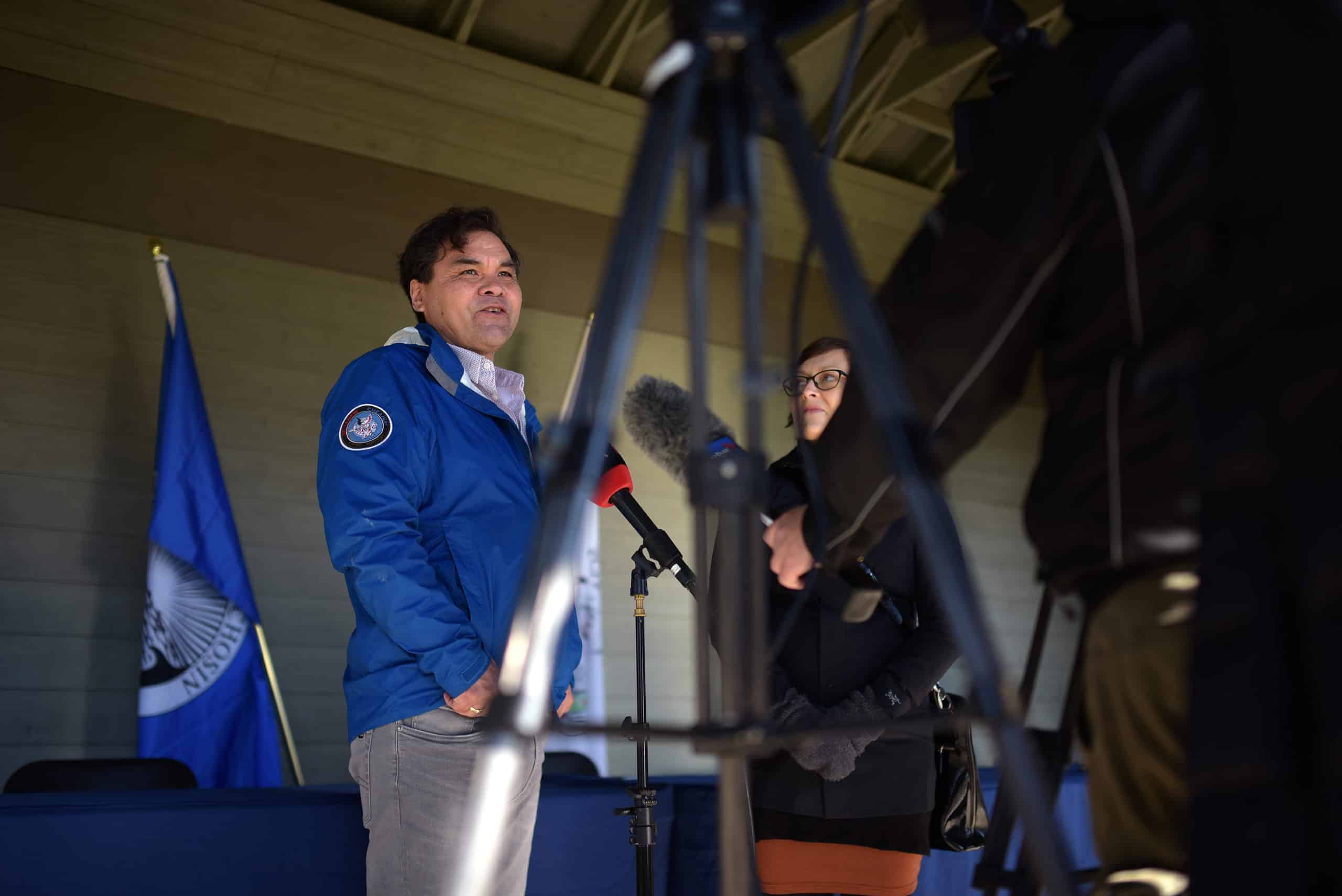 SC’IA⁄NEW First Nation Chief Russ Chipps takes questions from journalists at the announcement event. There is a microphone and tripod in the foreground.
