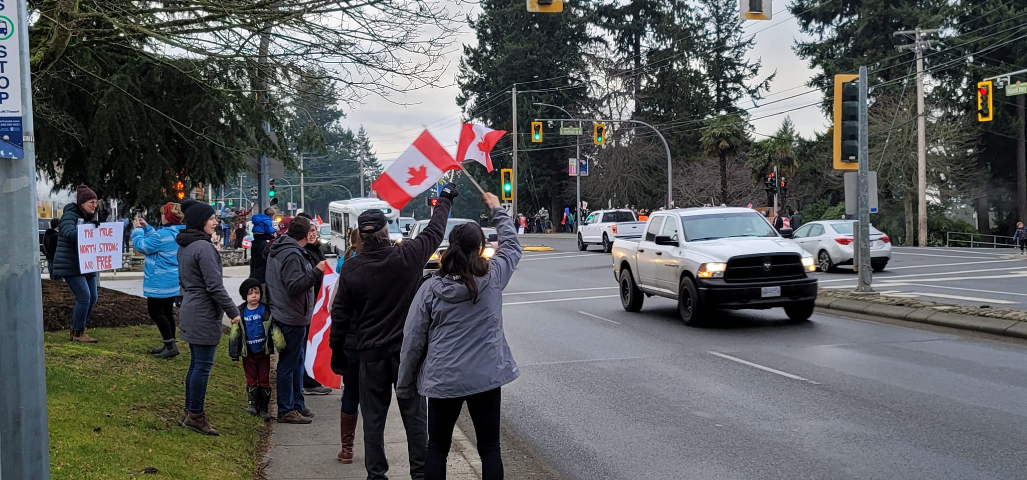 Protesters wave flags at a trucker convoy rally on Jan. 29 in Parksville, B.C