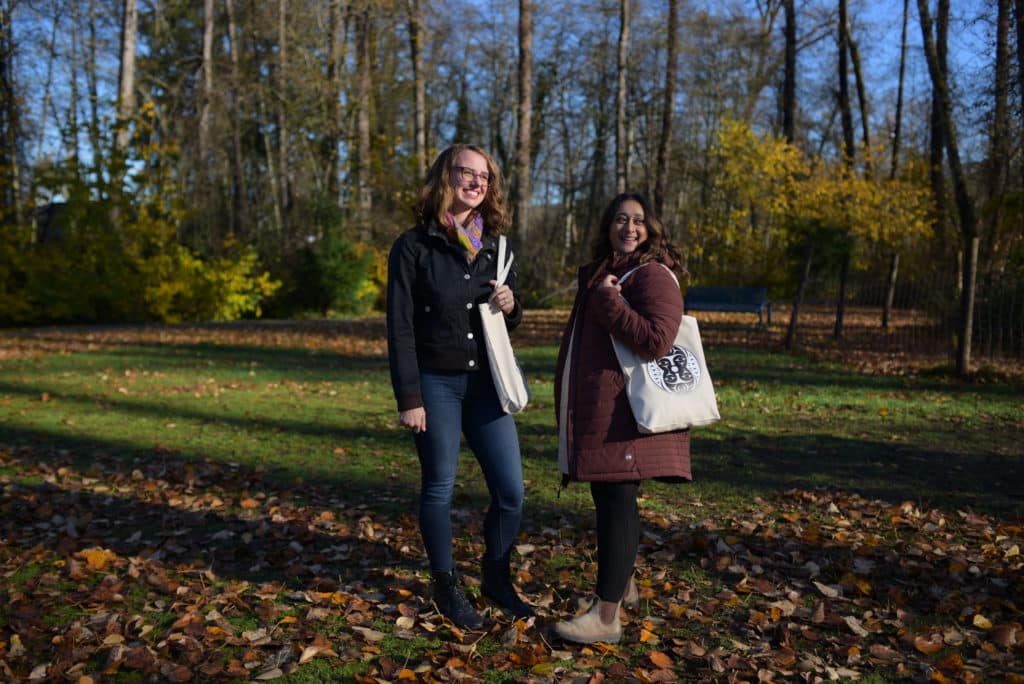 Jacqueline Ronson, left, and Shalu Mehta, right, pose and smile in front of a forested backdrop.