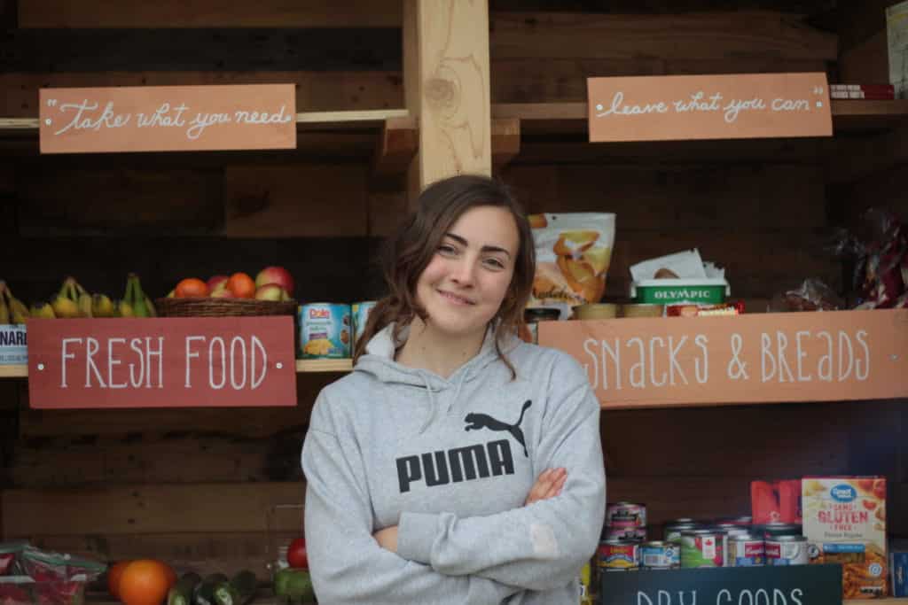 Blare Conlin stands in front of the food pantry, smiling and arms crossed