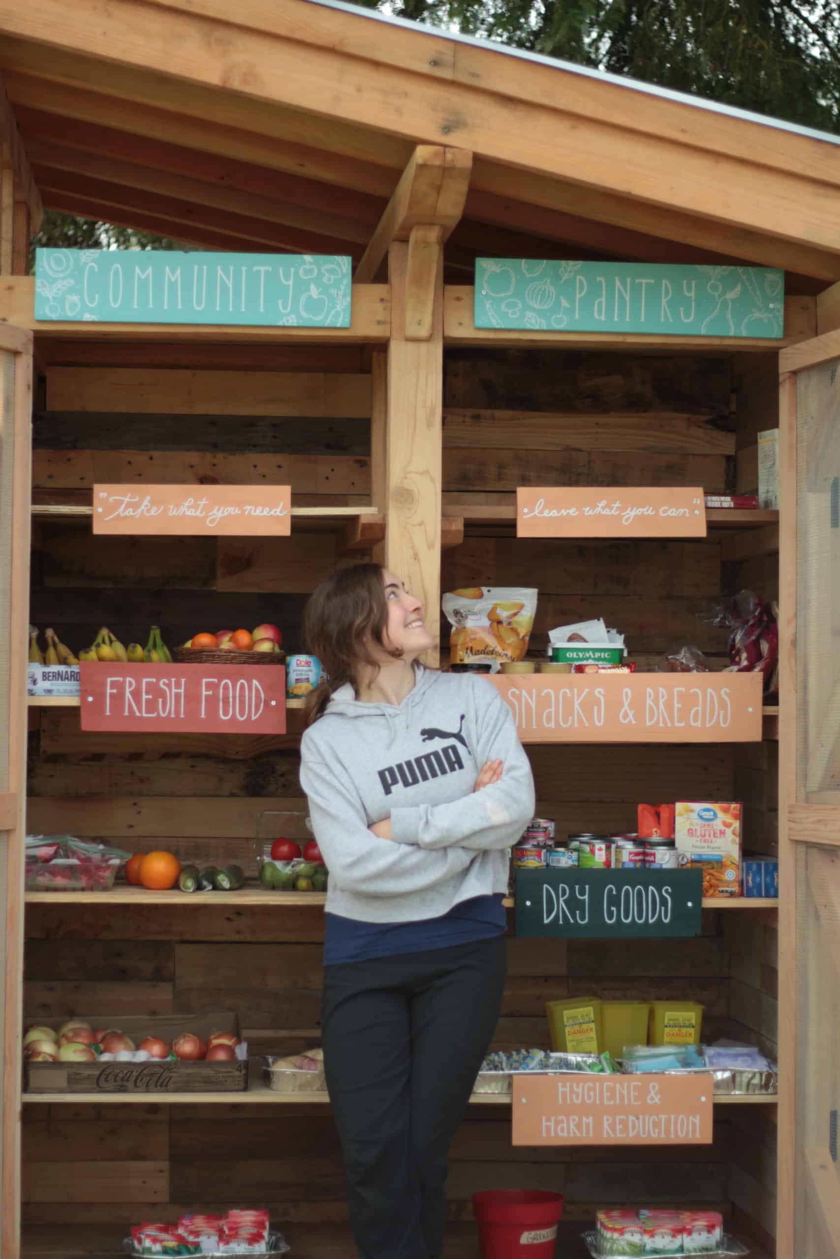 Blare Conlin stands in front of the food pantry, smiling and arms crossed