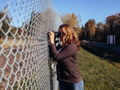 Jacqueline Ronson, reporter for The Discourse Cowichan, snaps a photo of the Vancouver Island Motorsport Circuit through the property's fence off Highway 18.