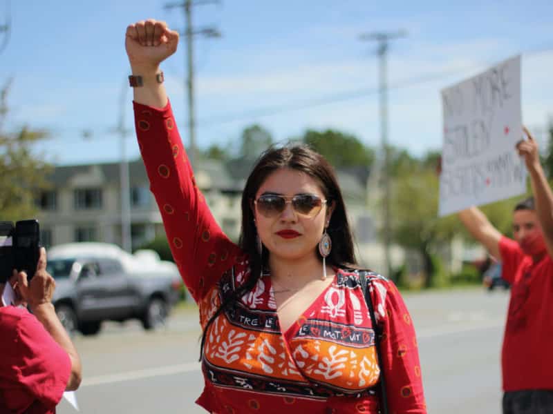 A woman in red raises a fist in a gesture of protest.