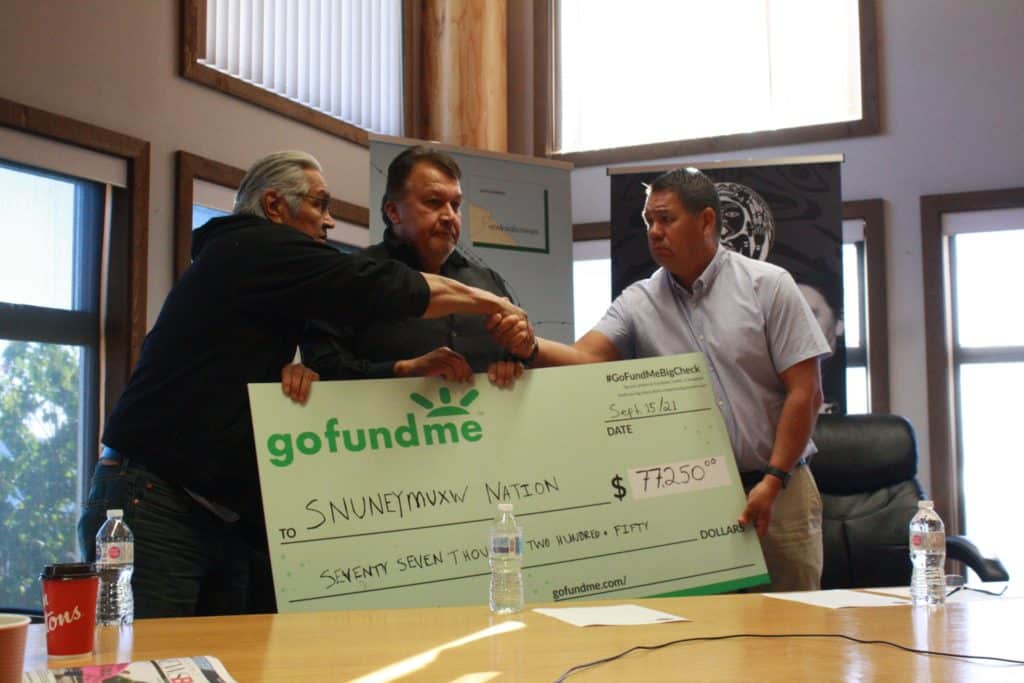 Chief Xumtilum (Michael) Wyse (right) shakes hands as he accepts a large GoFundMe cheque representing funds to support the search for unmarked graves on the ground of the former Nanaimo "Indian Hospital."