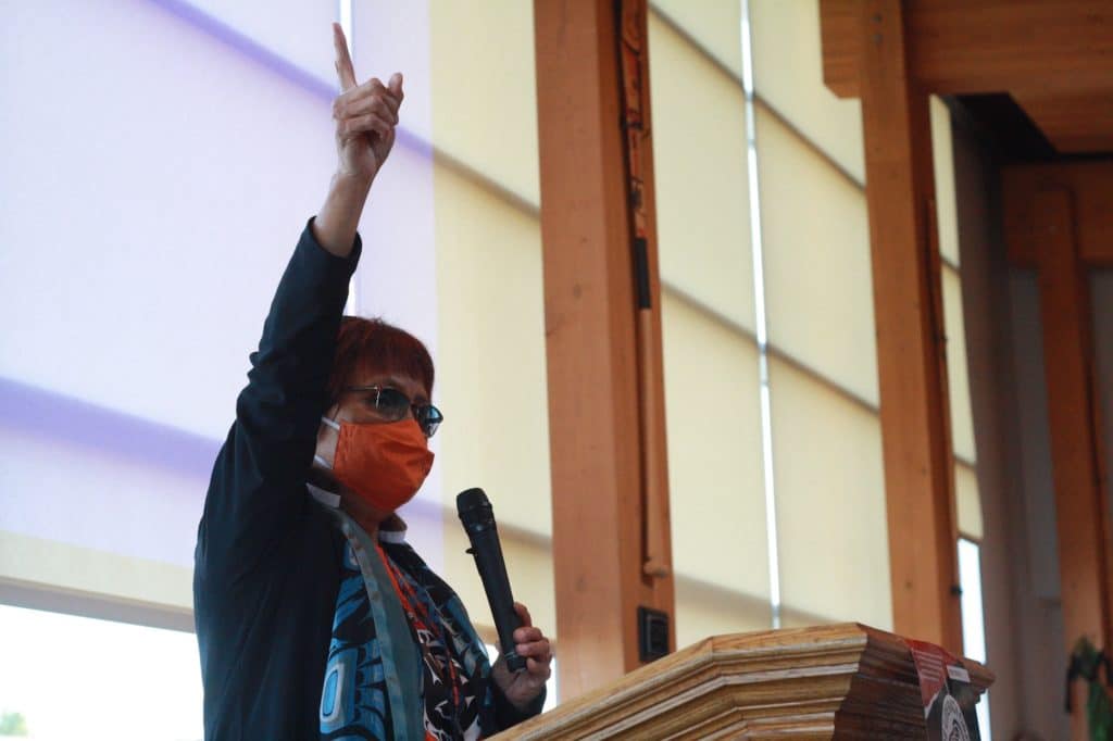 Elder Linda Jack raises her hand at the podium in a ceremony for The Literacy Circle