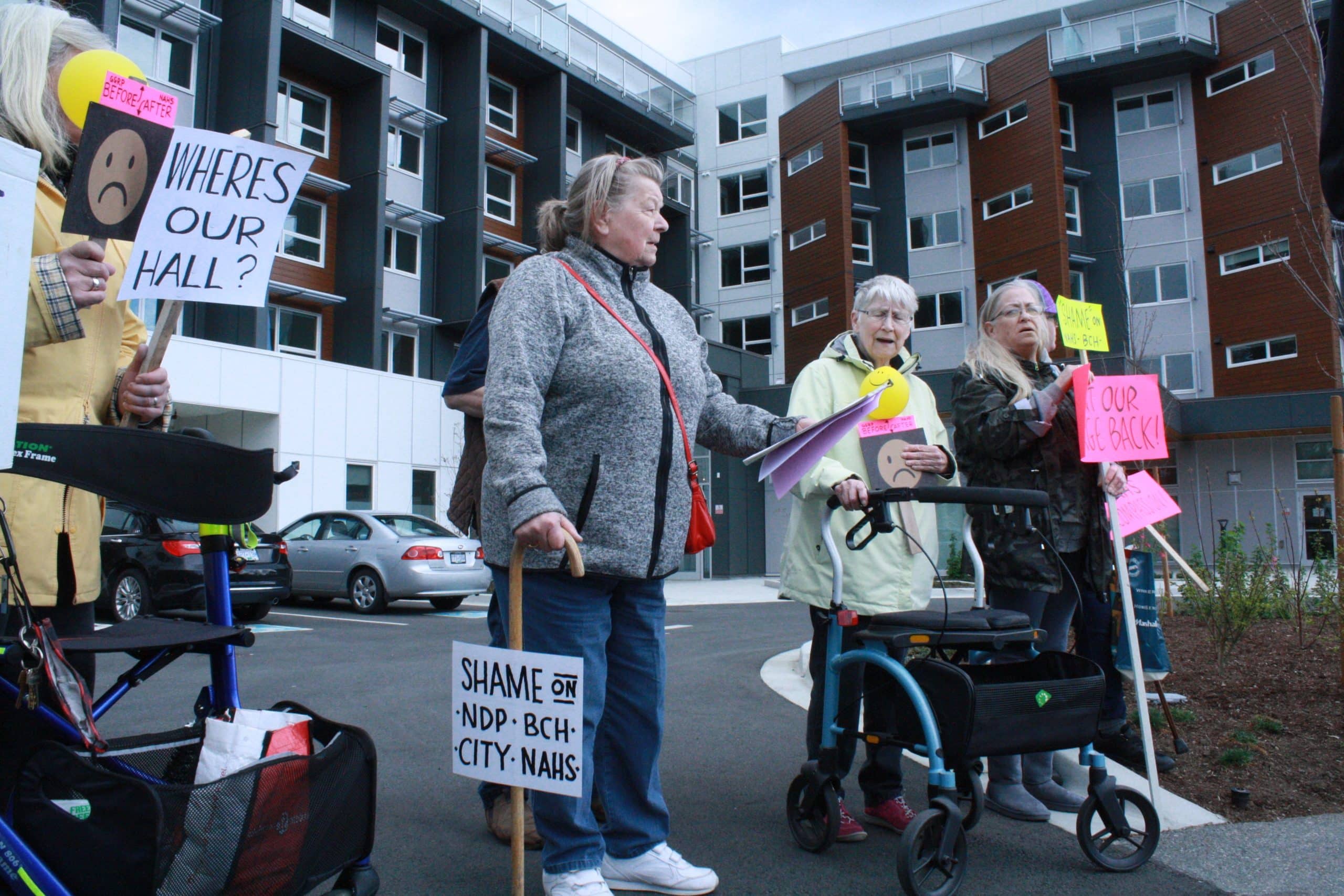 A group of tenants at Buttertubs seniors complex hold up signs in protest at the loss of services.