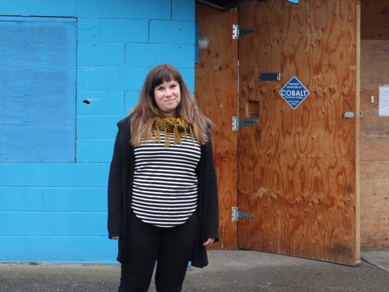 Woman stands outside building.