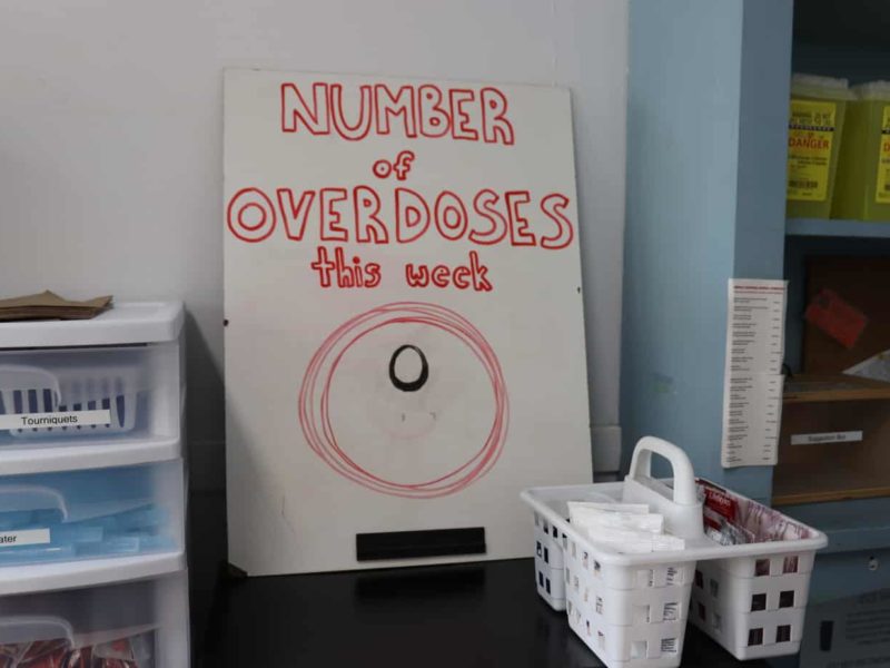 Photo of a white board that says "number of overdoses this week" with a zero below. And medical supplies.
