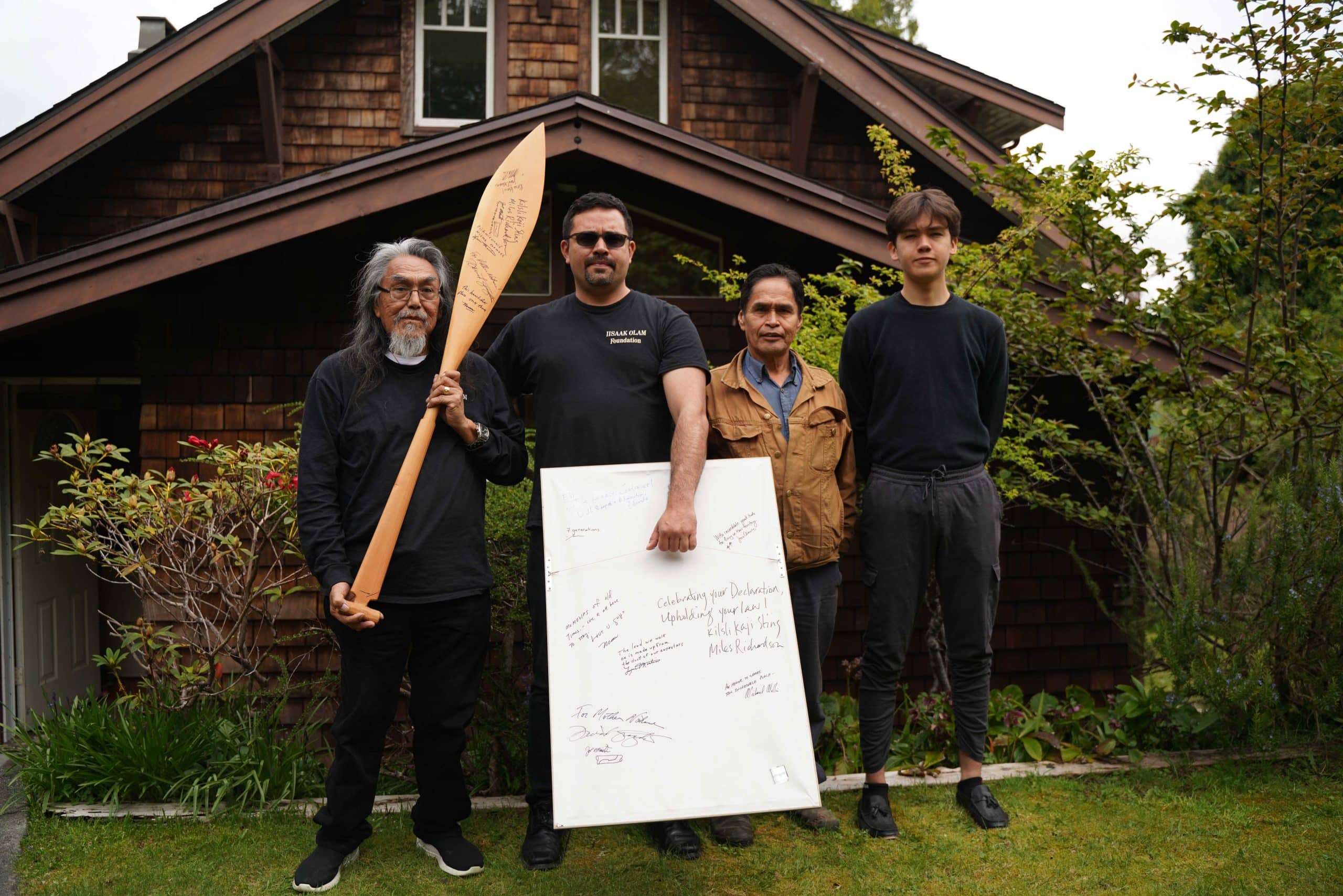 Levi Martin, Eli Enns, Joe Martin and Ian Enns hold a signed poster from 1984 which, on the flip side, says “Save Meares Island.”