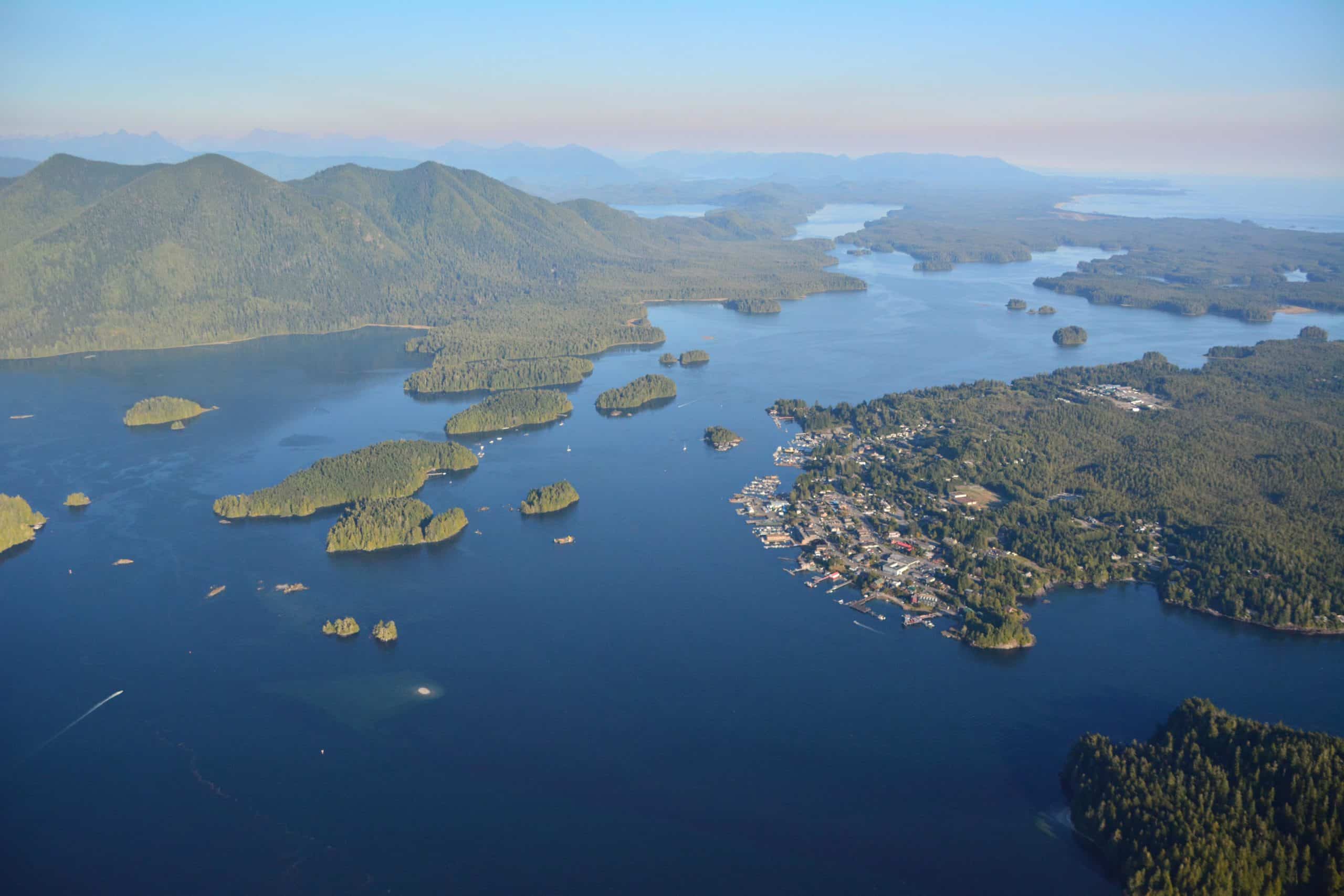 An arial photo showing Tofino, Wah-nuh-jus – Hilth-hoo-is (Meares Island) and the Village of Opitsaht.