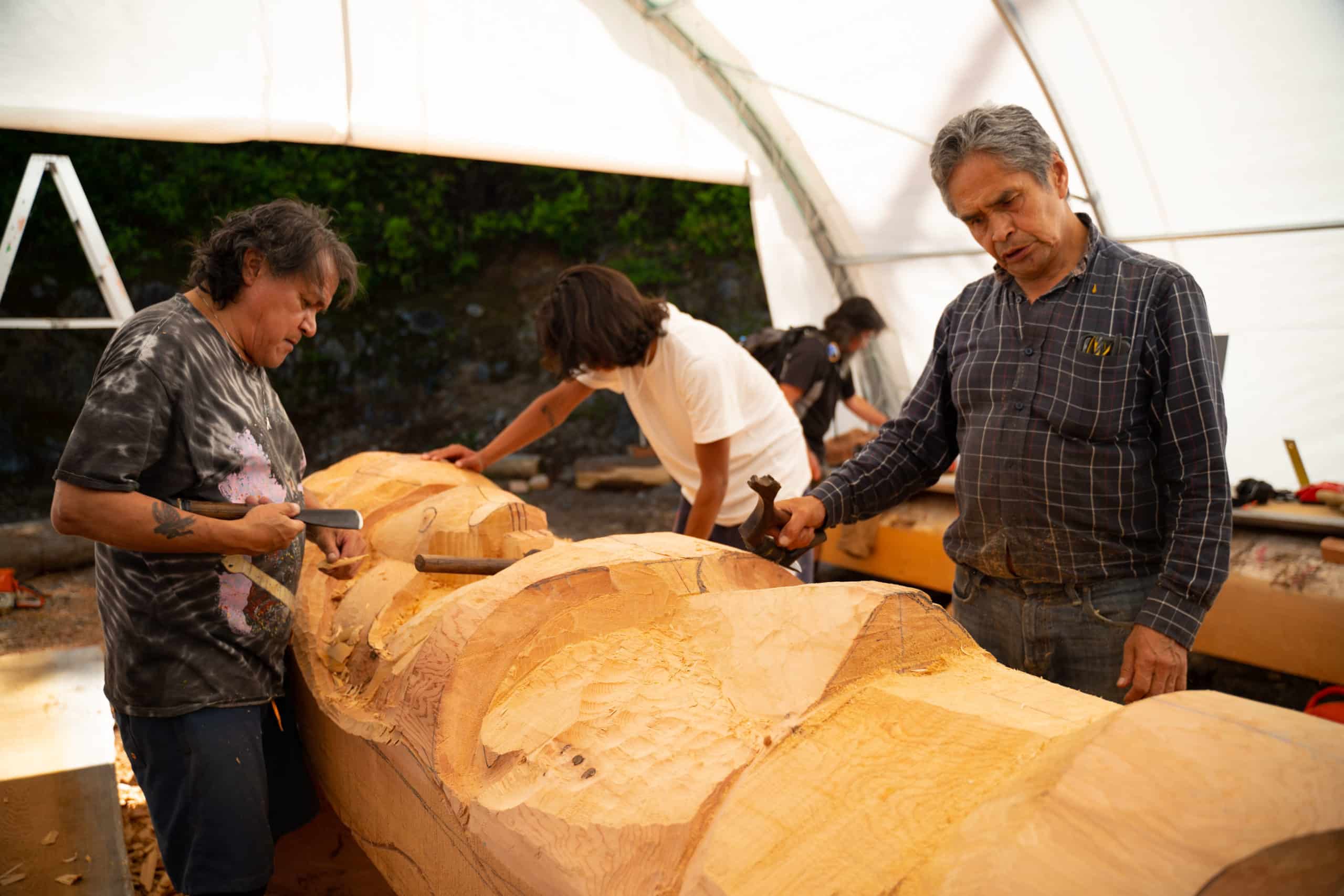 Pat Amos (left) and Joe Martin (right) carve a totem pole at the former Tofino Botanical Gardens