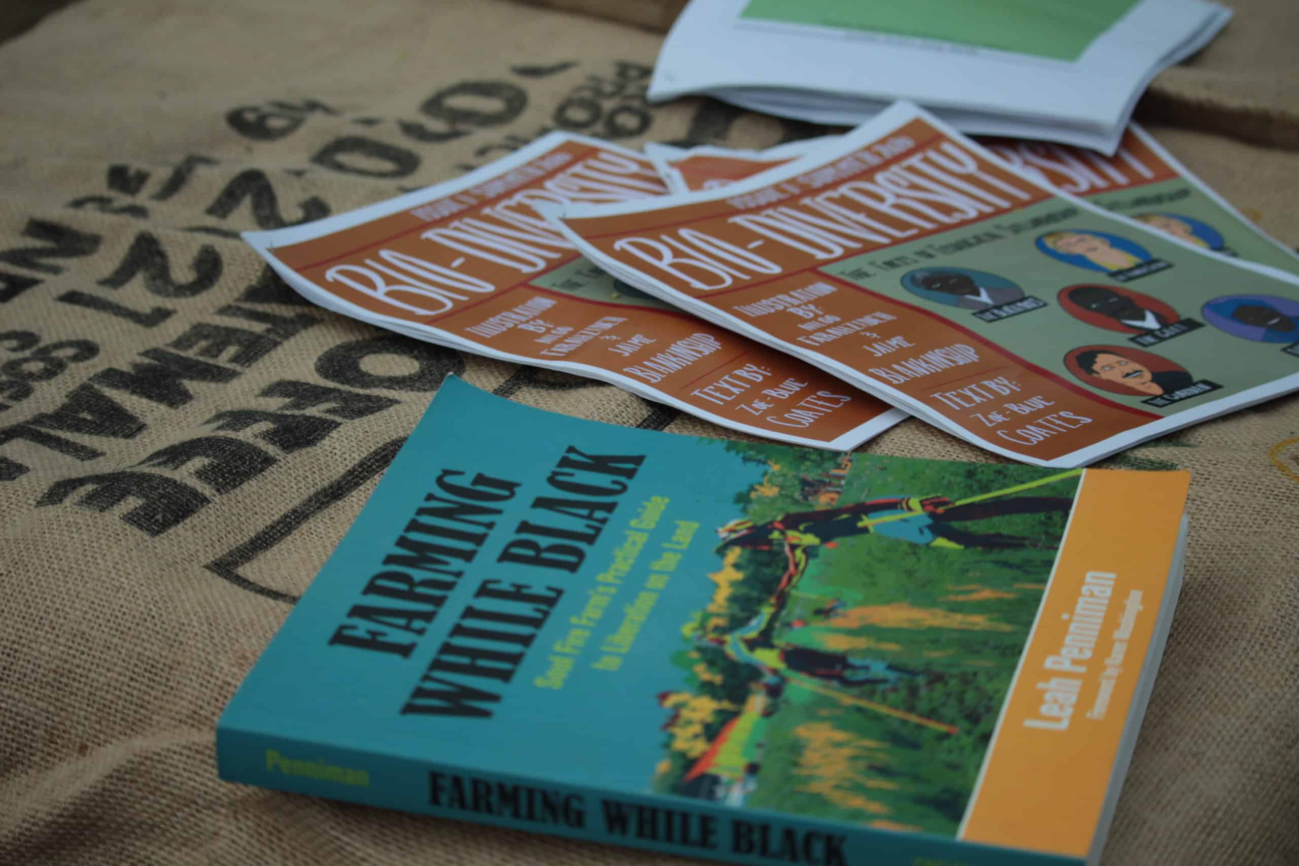 A book titled Farming While Black and pamphlets highlighting diversity are displayed on top of a large burlap bag at the workshop.