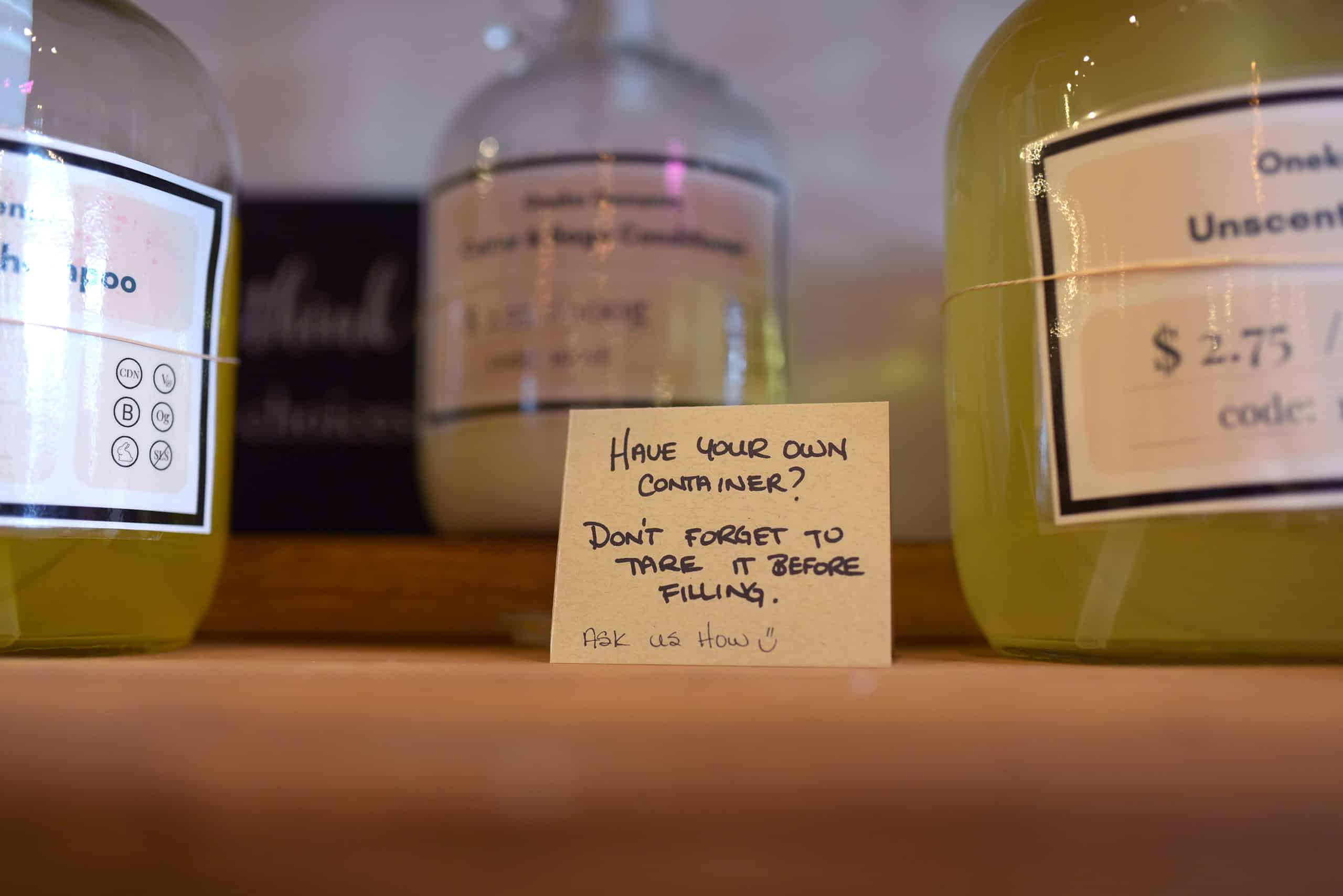 A note on a shelf at plentiFILL reminds customers to weigh their containers before filling them.