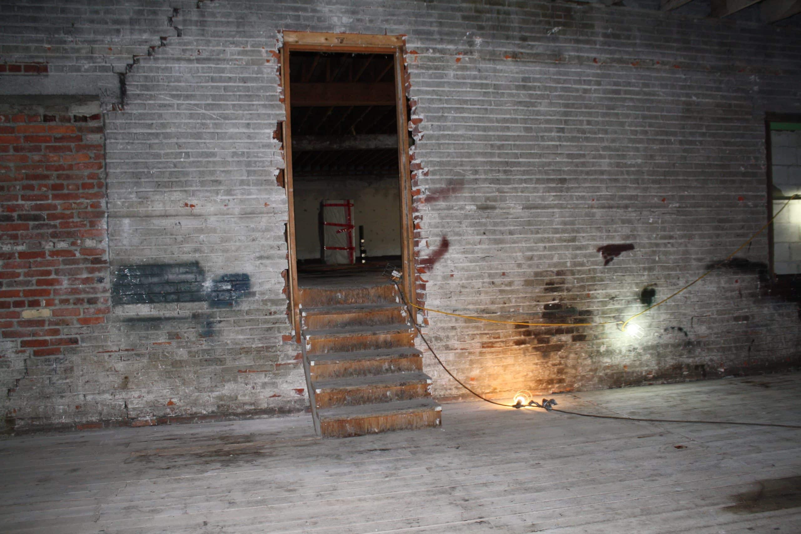 Stairs from the second floor to the third floor of the building show the old brick walls creating an artist loft feel.