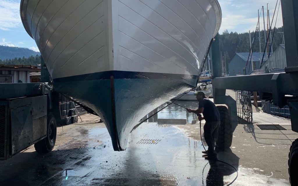 Simon Pidcock pressure washes the hull of a boat. Credit: Kalen Pidcock