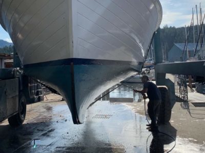 Simon Pidcock pressure washes the hull of a boat. Credit: Kalen Pidcock