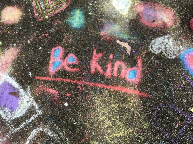 chalk drawing on pavement reads "be kind"