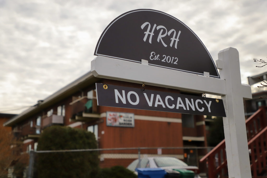 A sign displays "No Vacancy" in front of a rental building.