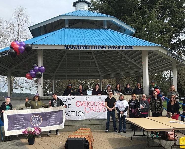 Advocates gather at Sway A Lana with a large white sign on the Day of Action on the Overdose Crisis Nanaimo, 2019