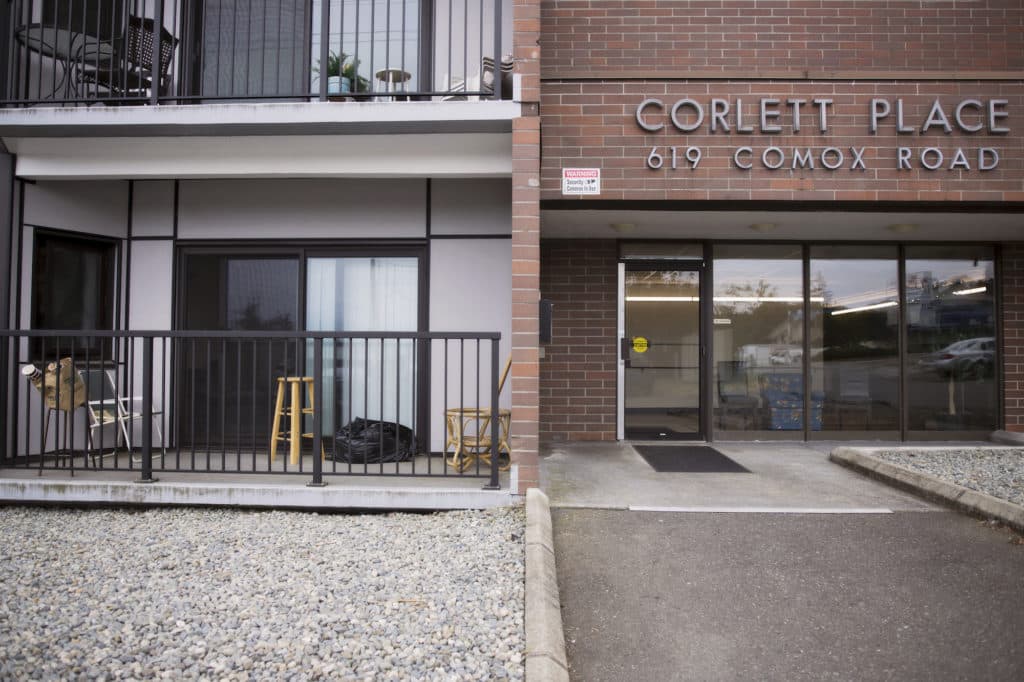 The front entrance of a 1970s-built complex shows patios and concrete.