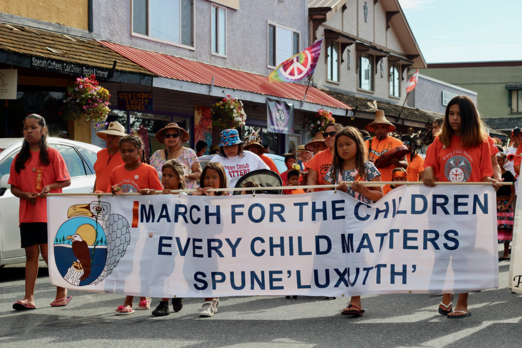 Children hold a large banner that reads "March For the Children; Every Child Matters; Spune’luxutth