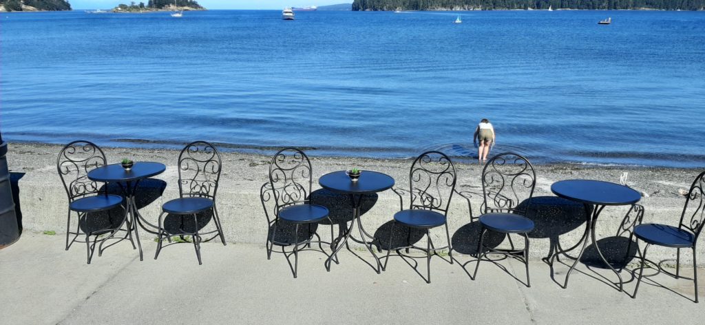 Black bistro-style tables line the boardwalk in front of the food truck, looking onto the water.