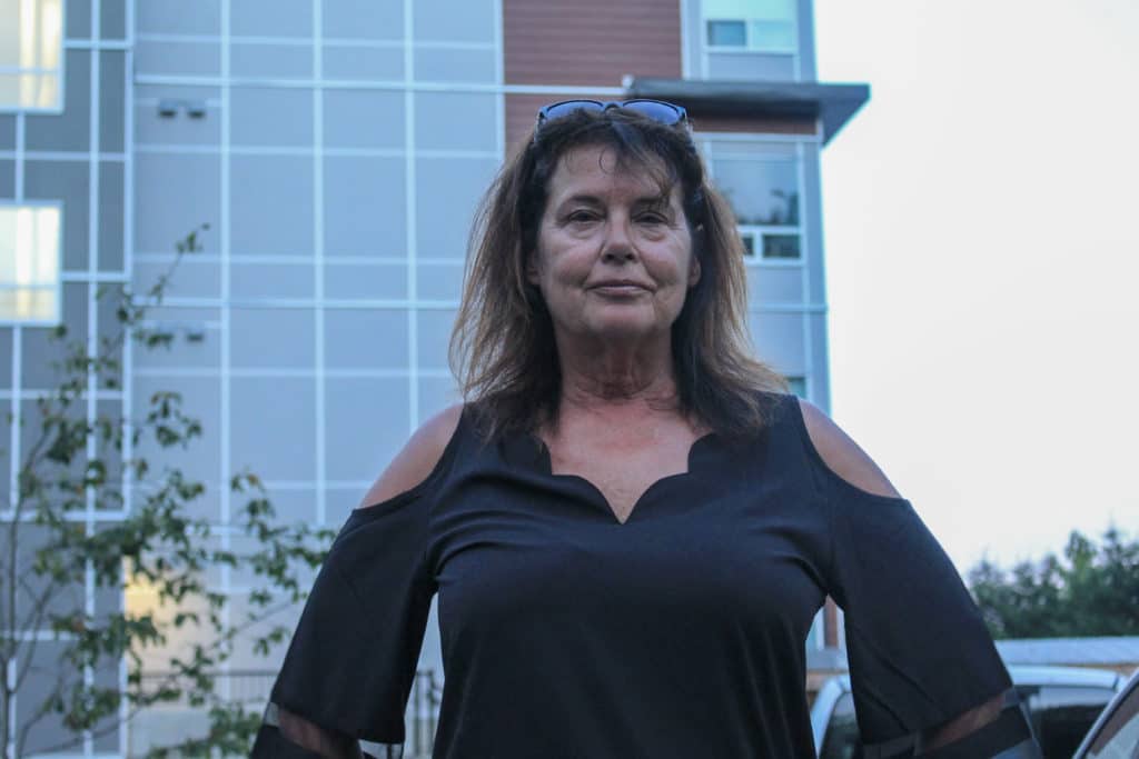 Anna Stolfi stands with her hands on her hips wearing a black shirt with cut-outs in the shoulder. The Magdalena building is behind her.