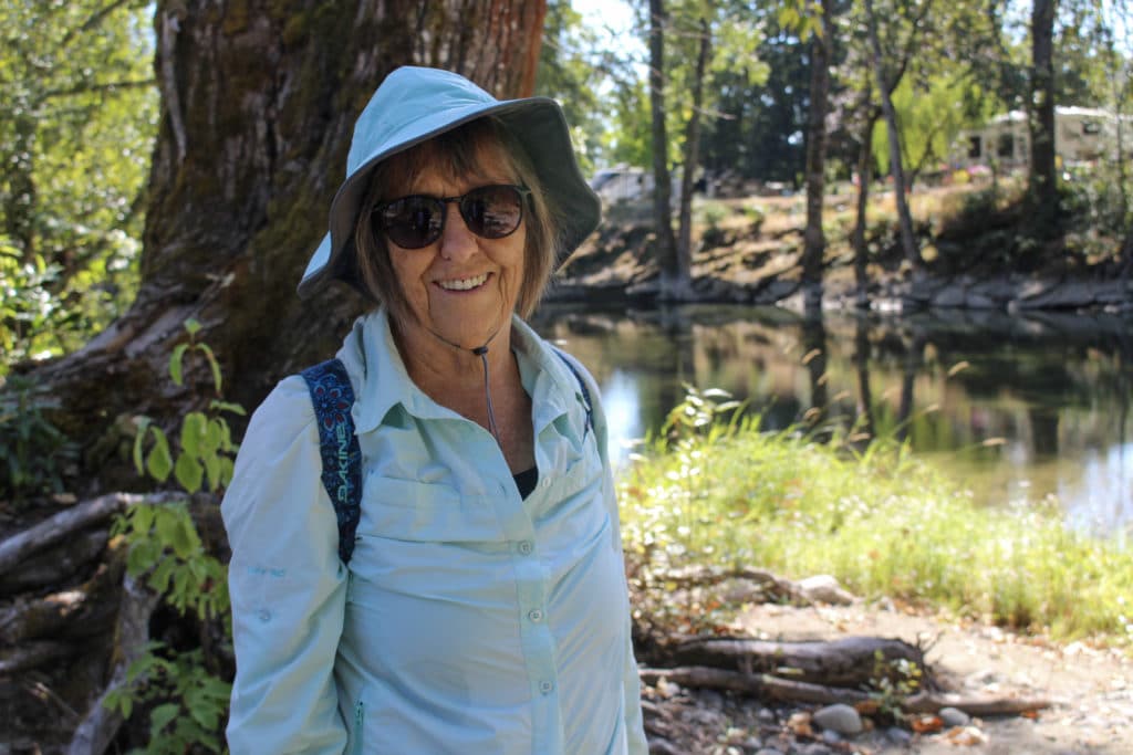 A woman in a blue shirt and hat smiles