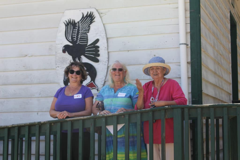 Three women stand, smiling