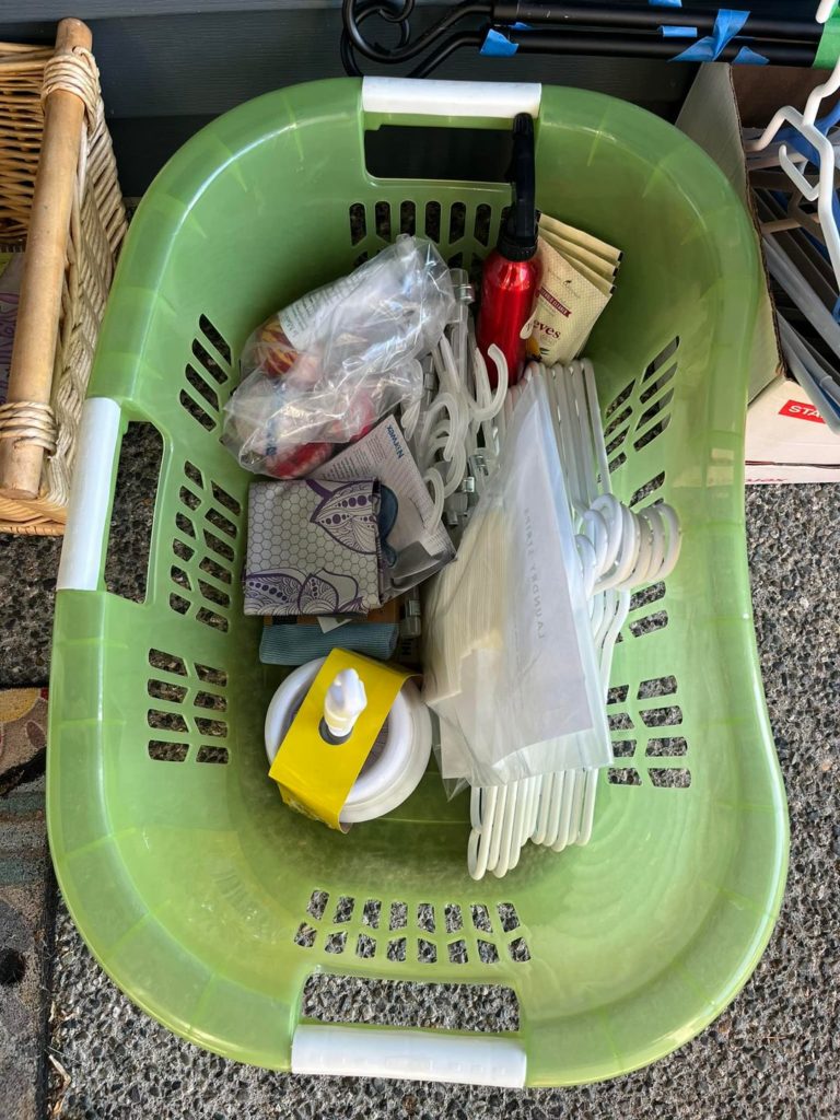 A green plastic basket sits full of cleaning supplies