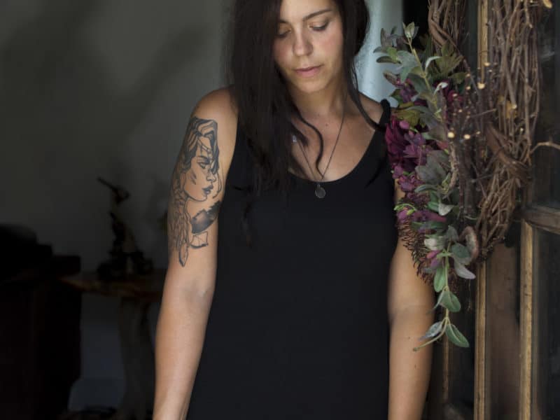 A woman stands holding a suitcase.