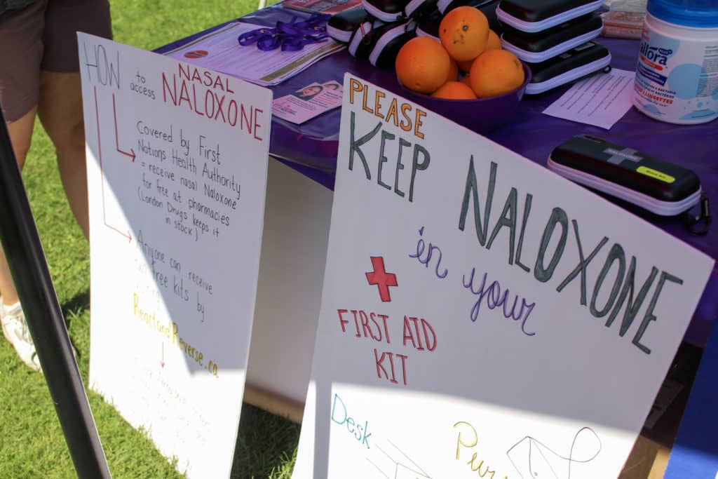 posters with information about naloxone lean against a table