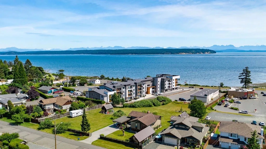 Aerial view of a large apartment complex by the ocean, and surrounding buildings