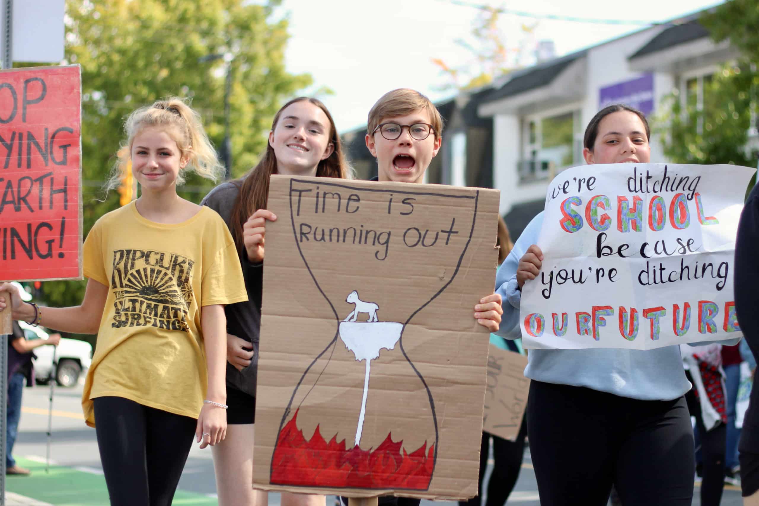 Four teens holding protest signs. "Time is running out." "We're ditching school because you're ditching our future."