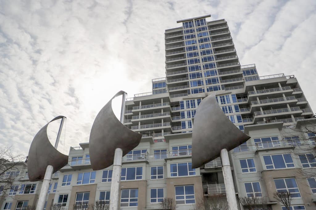 a photo of a sail statute is in the foreground of a high rise condo.