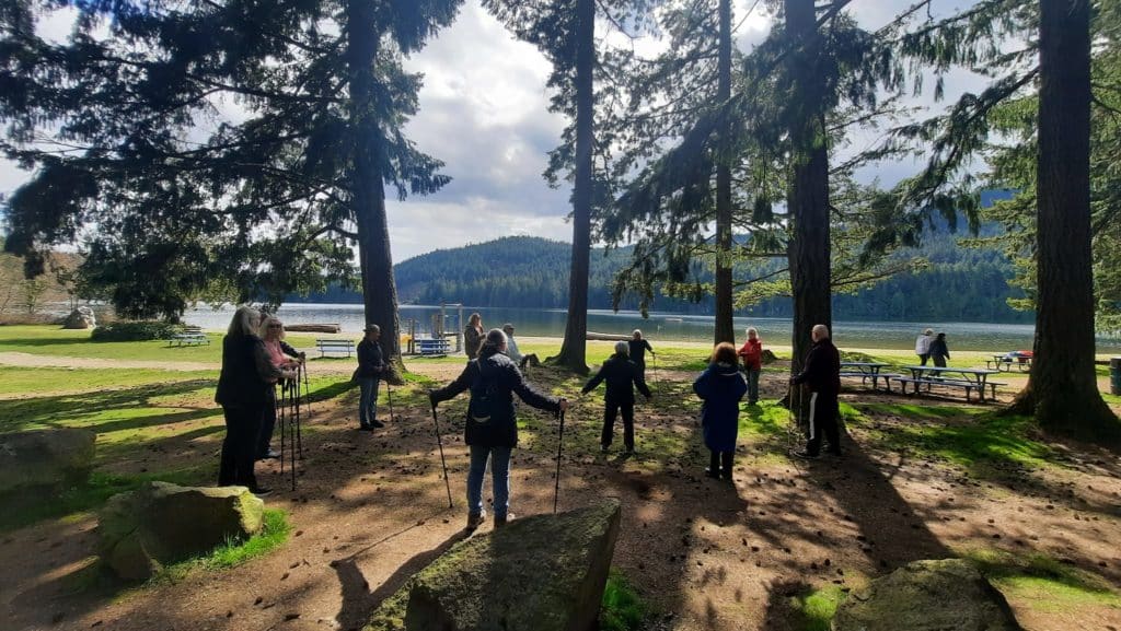 Nanaimo Family Life Association (NFLA) program participants gather around wildflowers at Bowen Park in the spring forest by the water.