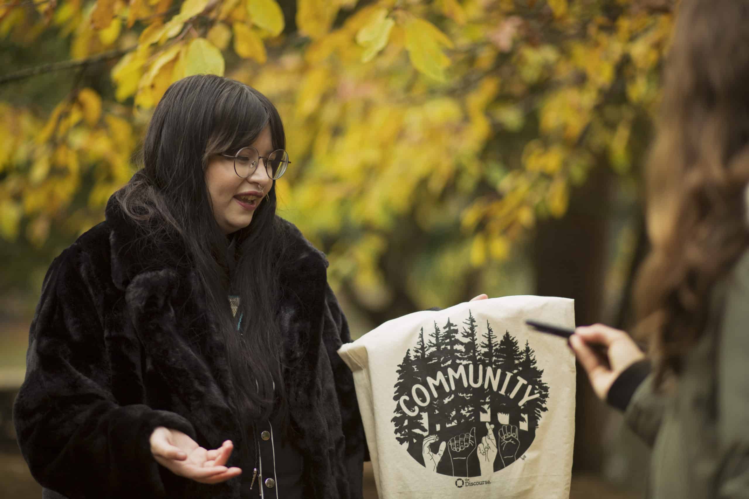 bailey macabre, dressed in black, holds a tote bag