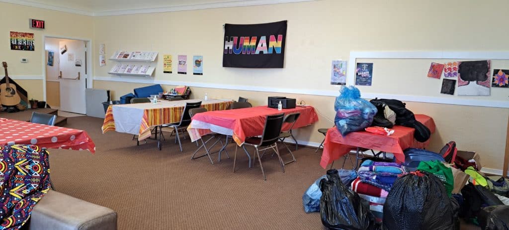 A warming centre with tables and a sign reads in rainbow colours, human.
